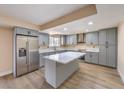 Updated kitchen features gray cabinets, stainless steel appliances, marble countertops, and an island with breakfast bar at 7477 Ullom Dr, Las Vegas, NV 89139
