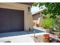 Two car garage with desert landscaping featuring a brown door and beige siding at 8873 Briar Bay Dr, Las Vegas, NV 89131