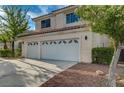Three-car garage of a tan two-story home with a concrete driveway at 9772 Galahad Point Ct, Las Vegas, NV 89147