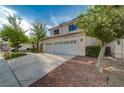 Tan two-story home featuring a three-car garage and desert landscaping at 9772 Galahad Point Ct, Las Vegas, NV 89147