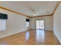 Spacious living room with wood-look floors, ceiling fan, and sliding glass door to the patio at 1793 Eagle Village Ave, Henderson, NV 89012
