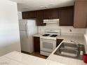 Functional kitchen featuring wood cabinets, white appliances, and tile countertops at 1830 N Pecos Rd # 252, Las Vegas, NV 89115
