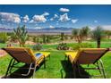 Relaxing backyard featuring lounge chairs on green grass with desert landscape and mountain views at 522 Via Ventana Dr, Mesquite, NV 89027