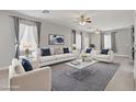 Bright living room with plush seating, a modern ceiling fan, and a stylish gray rug at 626 Taliput Palm Pl, Henderson, NV 89011