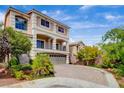 A landscaped front yard and a long driveway leads to an elegant two-story home with beautiful balconies at 6402 Parrot Ridge Ct, Las Vegas, NV 89139