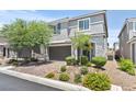 Charming two-story home featuring a gray facade, manicured landscaping, and a brick driveway at 7456 Tinley Creek Ave, Las Vegas, NV 89113