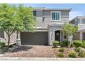 Charming two-story home featuring a gray facade, manicured landscaping, and a brick driveway at 7456 Tinley Creek Ave, Las Vegas, NV 89113