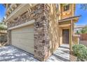 Close-up of a home's exterior showcasing stone accents, a two-car garage, and front entrance at 10072 Pelham Park Ave, Las Vegas, NV 89148