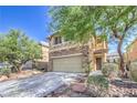 Attractive home featuring a stone facade, two-car garage, and desert landscaping at 10072 Pelham Park Ave, Las Vegas, NV 89148