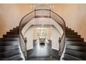 Grand foyer with a curved staircase, dark wood floors and views into the dining room at 10671 Capesthorne Way, Las Vegas, NV 89135