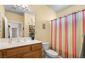 Cozy bathroom featuring a wood vanity, toilet and striped shower curtain at 1187 Mohave Dr, Mesquite, NV 89027