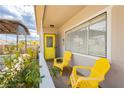 Cozy front porch with yellow chairs, a vibrant yellow door, and charming desert foliage at 67 Oklahoma Dr, Henderson, NV 89015