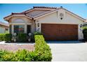 Beautiful single-story home with a terracotta roof, meticulously landscaped yard, and a wood-paneled two-car garage at 9355 W Viking Rd, Las Vegas, NV 89147
