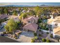 An aerial view showcases the lushly landscaped property and neighborhood with mountain views at 2108 Inverness Dr, Henderson, NV 89074