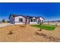 Stylish single-story home with desert landscaping, complemented by green grass accents and modern design elements at 2650 Underbrush Ave, Pahrump, NV 89048
