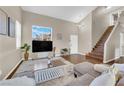 Open concept living room with a vaulted ceiling, wood staircase, and a large TV at 3659 Gerri Bay Ln, Las Vegas, NV 89147