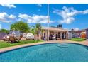 Backyard oasis featuring a sparkling pool, covered patio, and lush landscaping for relaxation at 4419 Lorna Pl, Las Vegas, NV 89107