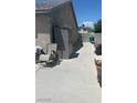 Concrete side yard with a dark grey storage shed and grey folding chairs with a view of a fenced yard at 901 Rockaway St, Las Vegas, NV 89145