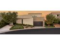 Contemporary home featuring clean lines, neutral tones, a dark garage door, and meticulously designed desert landscaping at 12 Desert Lake Ln, Henderson, NV 89011