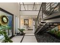 Bright foyer with modern staircase, decorative lighting, stone accents, and lush greenery at 12 Desert Lake Ln, Henderson, NV 89011