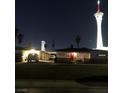 Exterior view of a well-lit home with a red door, set against the backdrop of the Stratosphere at night at 2217 Santa Ynez Dr, Las Vegas, NV 89104