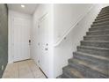 Bright entryway featuring tile floors, a white door, and a carpeted staircase with a white railing at 2343 Teatro Ave, Henderson, NV 89044