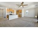 Open living room with a ceiling fan, neutral carpet, an adjacent kitchen, and natural light at 2343 Teatro Ave, Henderson, NV 89044