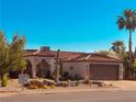 Beautiful desert-landscaped home with a Spanish-tile roof, arched entryway, and a two-car brown garage door at 444 Viewmont Dr, Henderson, NV 89015