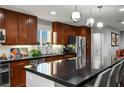 Modern kitchen featuring dark wood cabinets, stainless steel appliances, and a large black countertop island at 51 Morning Mimosa Ct, Henderson, NV 89012