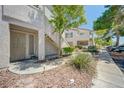 Condo featuring walkway, desert landscaping, building facade, and covered parking area in background at 5196 Mandalay Springs Dr # 101, Las Vegas, NV 89120