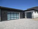Modern home with glass garage doors and a paved driveway leading to ample parking space at 6075 Dapple Gray Rd, Las Vegas, NV 89149
