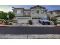 Street view of a two-story stucco home featuring a two-car garage and tidy landscaping at 672 Solitude Point Ave, Henderson, NV 89012