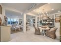 Open-concept living space with white tile floors and stylish furnishings, plus a kitchen in the background at 10140 Magnolia Creek St, Las Vegas, NV 89141