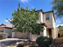 Delightful two-story house with a tan exterior, complemented by a charming front yard and mature trees at 147 Augusta Course Ave, Las Vegas, NV 89148