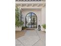 Inviting front entrance featuring a striking arched doorway, stone pathway, and lush landscaping at 1990 Country Cove Ct, Las Vegas, NV 89135