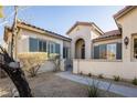 Stucco home showcasing a gated entryway with an arched alcove entrance and desert landscaping in the front at 9077 Creed Mountain Pl, Las Vegas, NV 89178