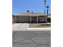 Inviting single-story home with a cozy front yard and a convenient two-car garage and mature palm trees at 1468 Harmony Hill Dr, Henderson, NV 89014