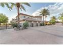 A tan stucco home with a three-car garage and a long driveway surrounded by mature landscaping at 743 N Orleans St, Henderson, NV 89015