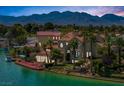 Waterfront home with a red dock, palm trees, beautiful lawn, and mountain views from this lakeside property at 2925 Coast Line Ct, Las Vegas, NV 89117