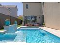 Inviting swimming pool with tiled waterfall feature and cozy patio furniture, perfect for outdoor relaxation at 3369 Ponicelli Ln, Henderson, NV 89044