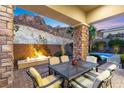 Covered patio boasts a stone fireplace, mountain views, and an outdoor dining area, perfect for entertaining guests at 34 Costa Tropical Dr, Henderson, NV 89011