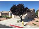 A side view of a house showing the driveway, garage, landscaping and a tree in the front yard at 5845 Swan Point Pl, Las Vegas, NV 89122