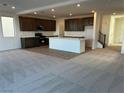Open-concept kitchen and living area featuring dark cabinetry, a center island, and neutral colored carpet at 8020 Texas Hills St, Las Vegas, NV 89113