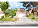 Charming house with a two-car garage, mature trees, green grass, and a concrete driveway at 912 Pro Players Dr, Las Vegas, NV 89134