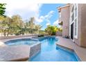 Backyard swimming pool and hot tub surrounded by lush trees and a black iron fence at 912 Pro Players Dr, Las Vegas, NV 89134