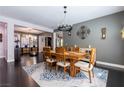 Elegant dining room with dark wood floors, stylish chandelier, and neutral gray walls at 10526 Harvest Wind Dr, Las Vegas, NV 89135