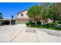 Attractive two-story stucco home with a two-car garage, carport, mature trees, and grass at 1345 Morning Sun Way, Las Vegas, NV 89110