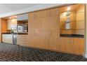 Condo kitchenette with wood cabinets, countertop, microwave, TV, and decorative shelving against patterned black and white carpeting at 2000 N Fashion Show Dr # 2704, Las Vegas, NV 89109