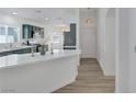 Stylish kitchen with quartz countertops and green cabinets, open to the entryway and living spaces at 4369 Meadowlark Wing Way, North Las Vegas, NV 89084