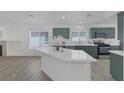 The open kitchen features green cabinets, a center island, and modern stainless appliances at 4369 Meadowlark Wing Way, North Las Vegas, NV 89084